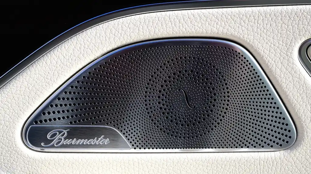 Component speakers and coaxial speakers laid out on a garage workbench beside an open car door.