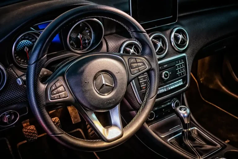 Driver pressing steering wheel controls in a car interior with the radio dashboard visible