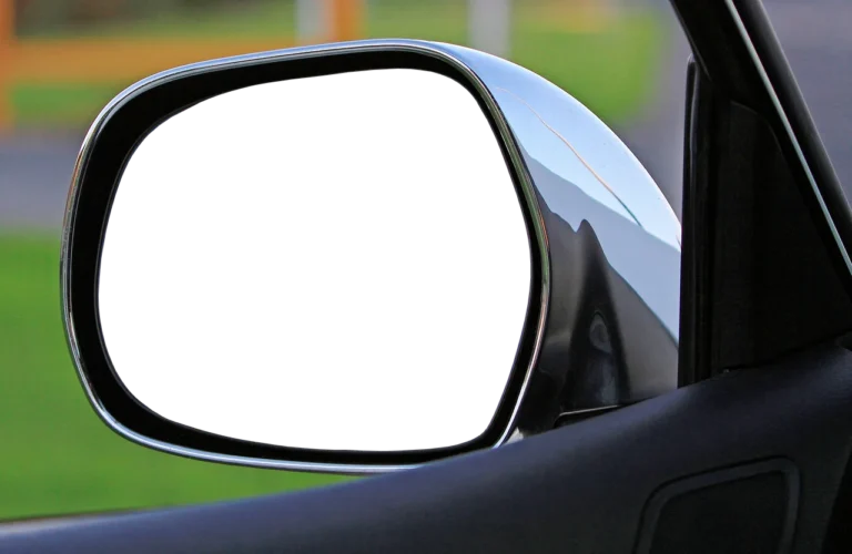 Driver compares a rearview mirror monitor and wiring options beside an open car door.