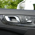 Car audio installer measuring a speaker opening in a sedan door with trim removed