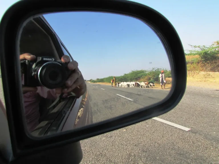 A driver checks a rear dash cam display in a parked car at dusk