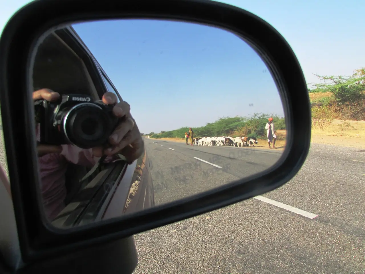 A driver checks a rear dash cam display in a parked car at dusk