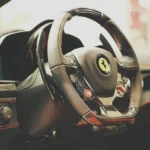 Car steering wheel controls next to a center dash stereo in a sunlit interior.