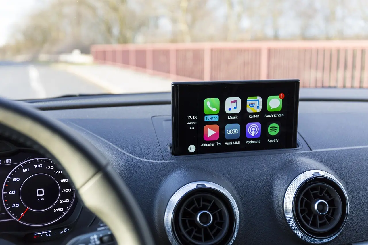 Driver using wireless CarPlay in a car interior with a phone on the dashboard near the stereo